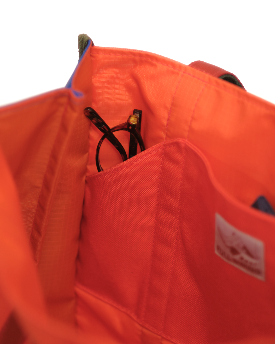 Close-up of an orange bag with a visible brand logo on a white background