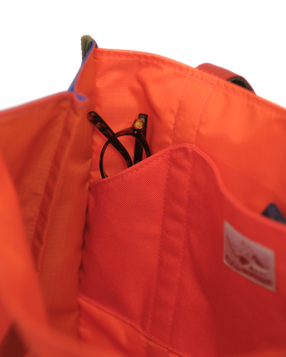Close-up of an orange bag with a visible brand logo on a white background